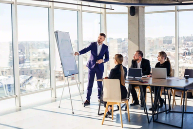 business-people-working-together-modern-office-with-cityscape-view-director-tells-staff-about-new-technologies-office-work-concept_1_1.webp